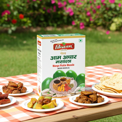 Box of Mango Pickle Masala with plates of food on a checkered table cloth outdoors.