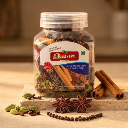 Jar of Indian Garam Masala Sabut with spices on a wooden surface kichnam container