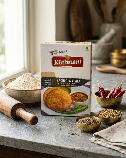 Kichnam Kachori Masala packaging on a kitchen counter with ingredients and utensils.