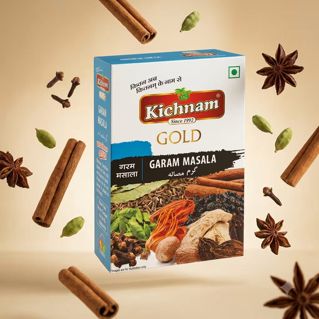 A box of Kichnam Gold Garam Masala spice mix is centered against a warm beige background, surrounded by floating cinnamon sticks, whole spices, and green cardamom pods. The packaging is white and blue with a prominent red Kichnam logo.
